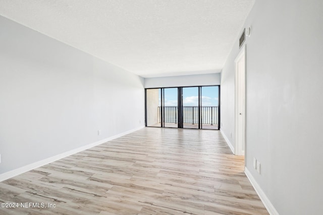 spare room with light hardwood / wood-style floors and a textured ceiling