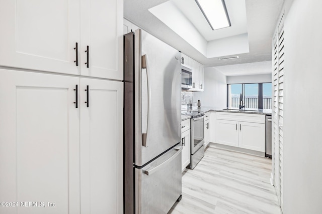 kitchen with light wood-type flooring, white cabinetry, sink, and appliances with stainless steel finishes