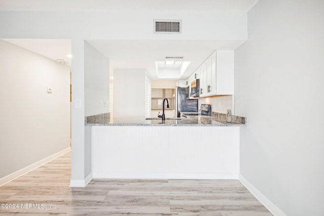 kitchen featuring light wood-type flooring, white cabinetry, light stone counters, and sink