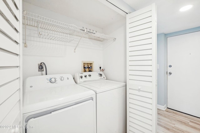 clothes washing area featuring separate washer and dryer and light hardwood / wood-style floors