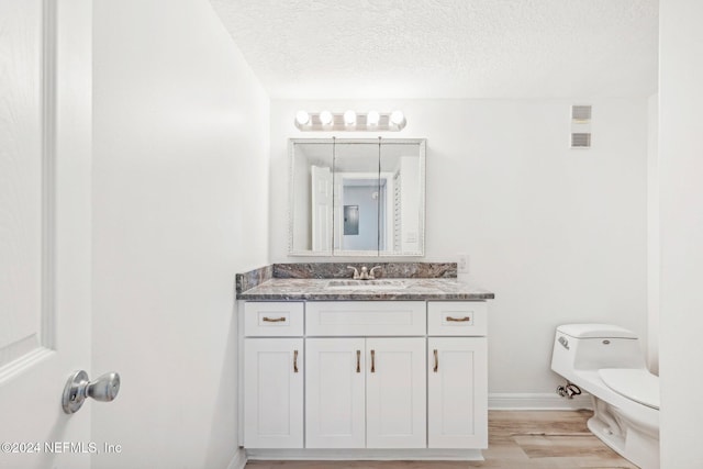 bathroom featuring hardwood / wood-style flooring, vanity, toilet, and a textured ceiling