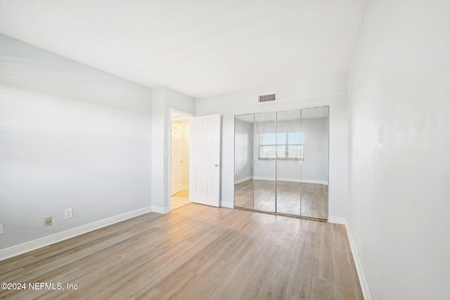 unfurnished bedroom with light wood-type flooring and a closet