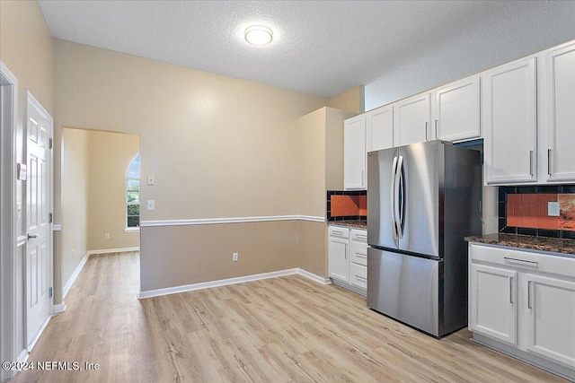 kitchen with backsplash, stainless steel refrigerator, light hardwood / wood-style flooring, and white cabinets