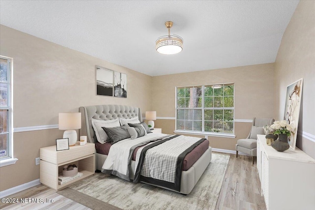 bedroom featuring a textured ceiling and light hardwood / wood-style flooring