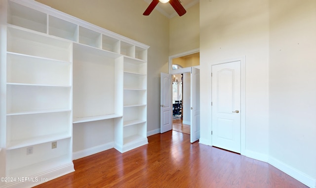 interior space with hardwood / wood-style floors, ceiling fan, and a towering ceiling