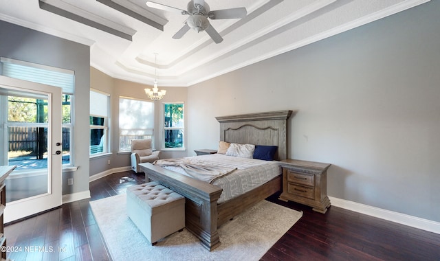 bedroom featuring dark hardwood / wood-style floors, ornamental molding, ceiling fan with notable chandelier, and a tray ceiling