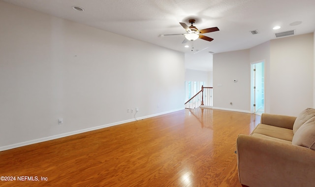 living room featuring ceiling fan, a textured ceiling, and light hardwood / wood-style flooring