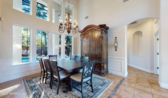 tiled dining area featuring a towering ceiling and a notable chandelier