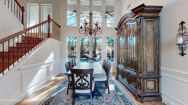 dining area with ceiling fan with notable chandelier, a towering ceiling, and a wealth of natural light