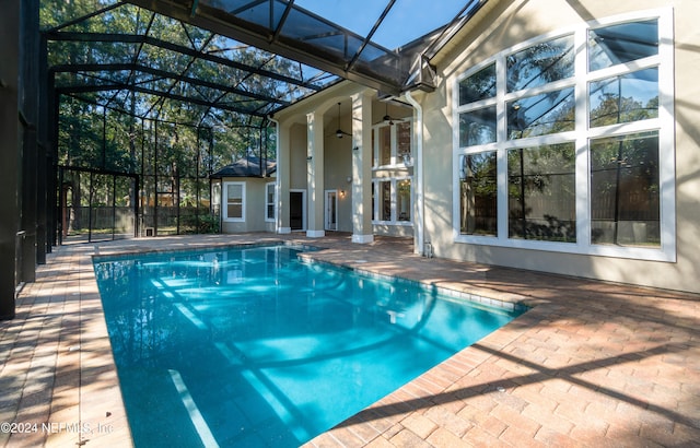 view of swimming pool featuring ceiling fan, a lanai, and a patio