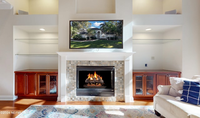 living room with light hardwood / wood-style floors, a high ceiling, and a tiled fireplace