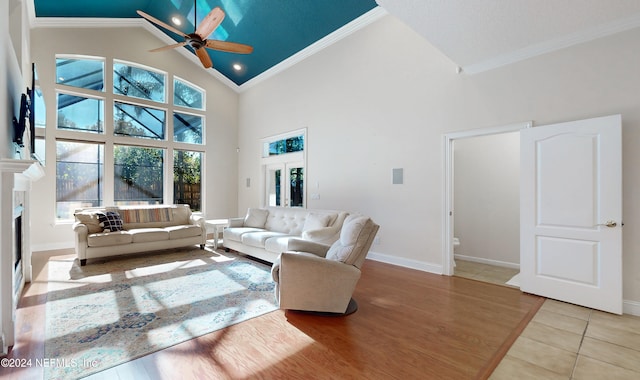 living room with ceiling fan, high vaulted ceiling, ornamental molding, and light wood-type flooring