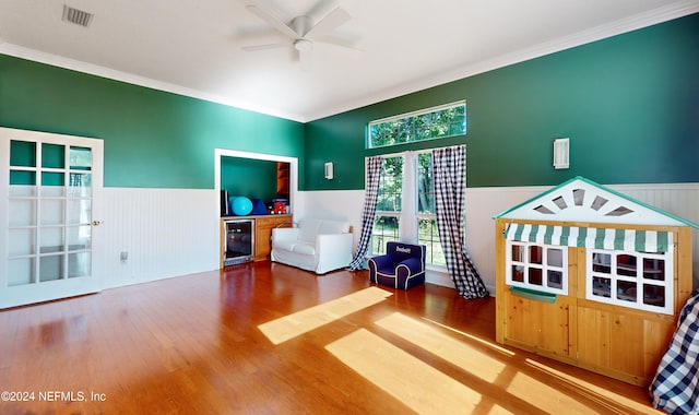 sitting room featuring hardwood / wood-style flooring, ceiling fan, crown molding, and wine cooler