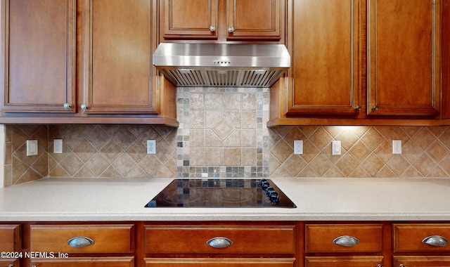 kitchen featuring decorative backsplash, black electric cooktop, and wall chimney exhaust hood