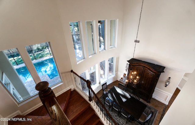 stairs featuring wood-type flooring, a high ceiling, and a chandelier