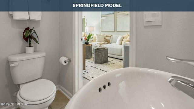 bathroom with tile patterned floors, a washtub, and toilet