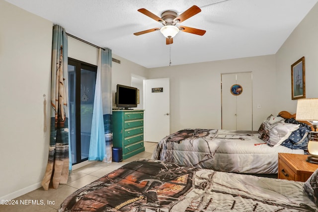 bedroom with a textured ceiling, ceiling fan, and light tile patterned floors