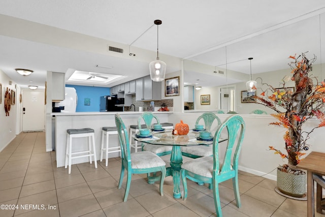 tiled dining room with ceiling fan and sink