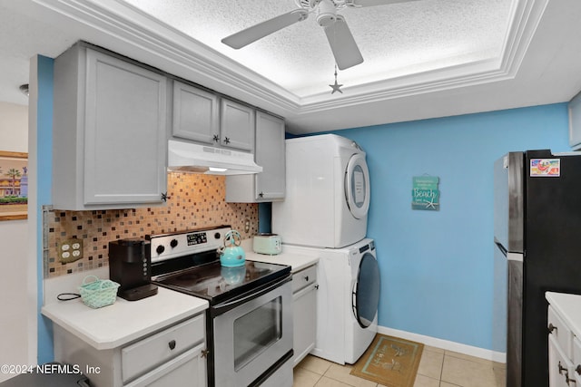 kitchen featuring appliances with stainless steel finishes, backsplash, light tile patterned flooring, a textured ceiling, and stacked washing maching and dryer