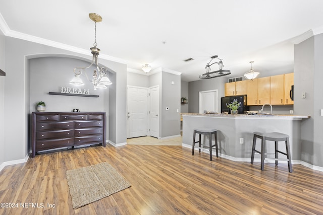 kitchen with black appliances, light brown cabinets, kitchen peninsula, and light hardwood / wood-style floors