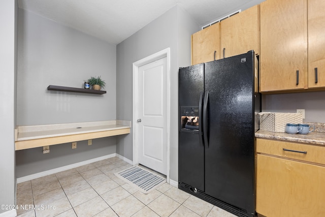 kitchen with black fridge with ice dispenser, light tile patterned floors, and built in desk