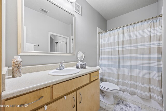 bathroom with tile patterned floors, a textured ceiling, vanity, toilet, and curtained shower