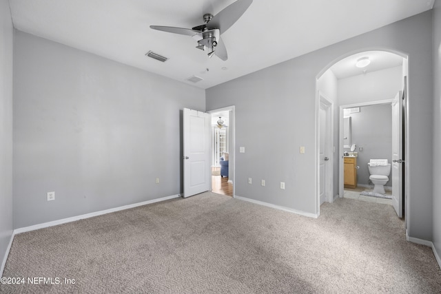 unfurnished bedroom featuring ceiling fan, ensuite bathroom, and light colored carpet