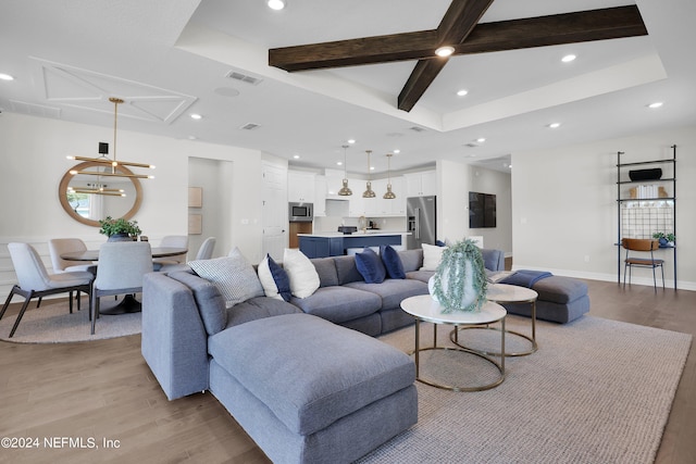 living room with sink, a tray ceiling, beamed ceiling, a notable chandelier, and light hardwood / wood-style floors