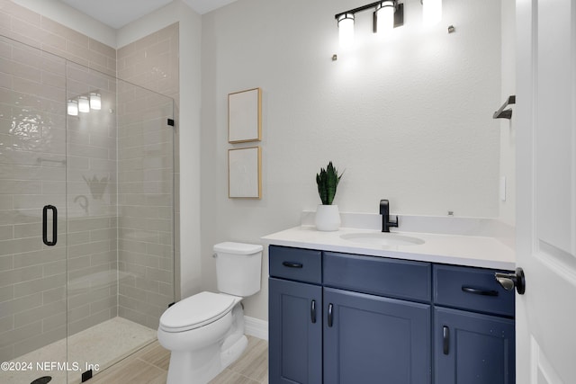 bathroom featuring tile patterned flooring, vanity, toilet, and a shower with door