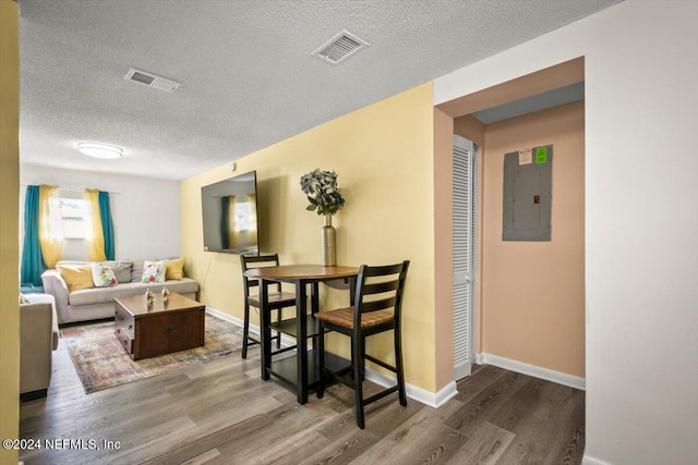 dining room with hardwood / wood-style flooring, a textured ceiling, and electric panel