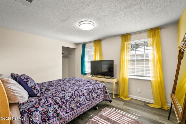 bedroom featuring a closet, a textured ceiling, dark hardwood / wood-style floors, and multiple windows