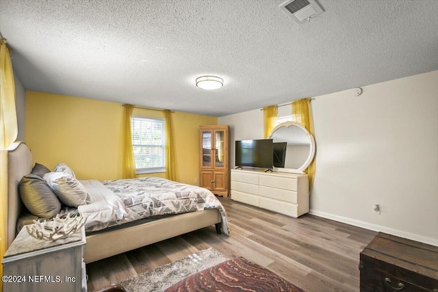 bedroom with a textured ceiling and hardwood / wood-style flooring