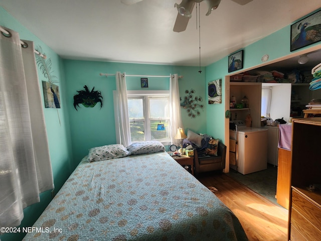 bedroom featuring ceiling fan, washer and clothes dryer, and hardwood / wood-style flooring