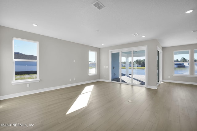 empty room featuring hardwood / wood-style floors, a textured ceiling, and a water view