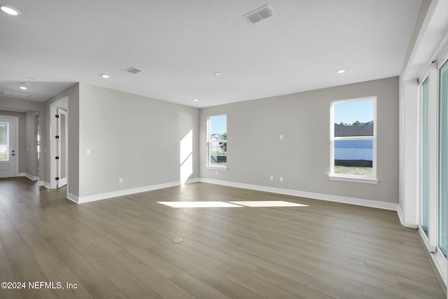 unfurnished room with light wood-type flooring and a textured ceiling