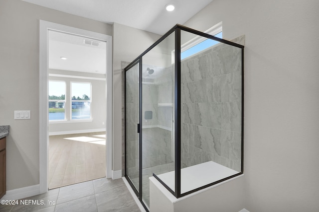 bathroom with a water view, vanity, wood-type flooring, and an enclosed shower