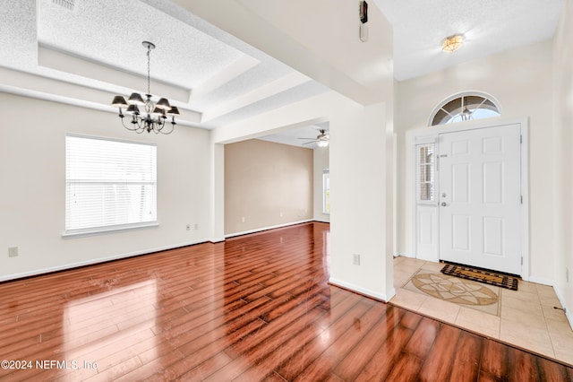 entryway with ceiling fan with notable chandelier, a textured ceiling, and hardwood / wood-style flooring