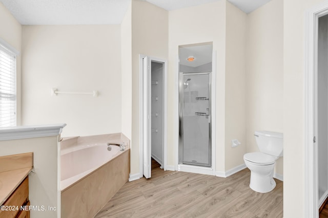 full bathroom with wood-type flooring, a textured ceiling, shower with separate bathtub, and toilet