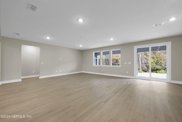 spare room with a textured ceiling and light hardwood / wood-style floors