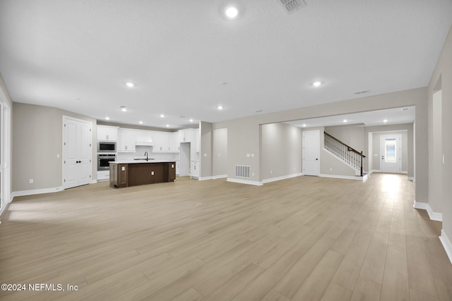 unfurnished living room with light wood-type flooring and sink