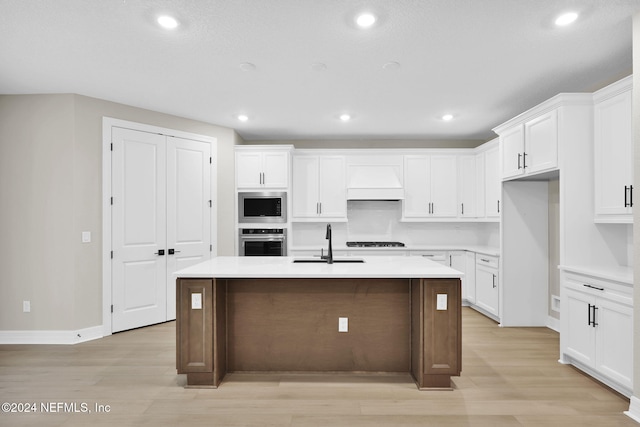 kitchen with sink, white cabinetry, stainless steel appliances, and an island with sink