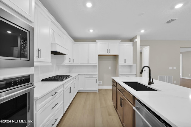 kitchen with white cabinets, sink, light wood-type flooring, and stainless steel appliances