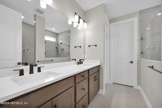 bathroom featuring a tile shower, vanity, and tile patterned floors