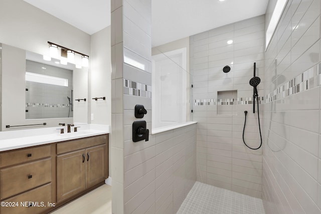 bathroom with a tile shower, vanity, and plenty of natural light