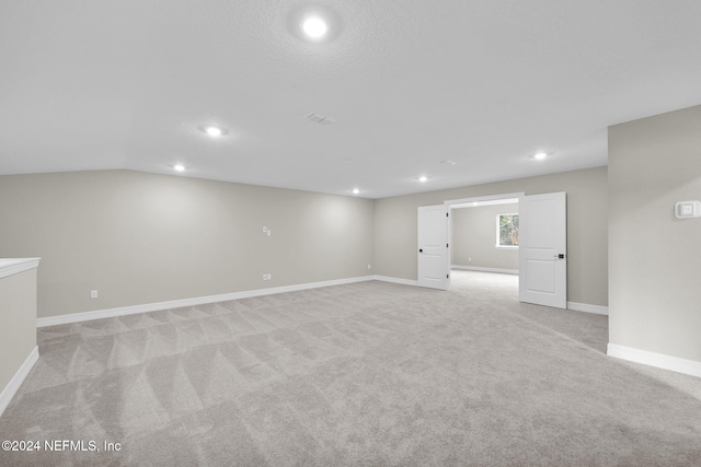 carpeted empty room featuring vaulted ceiling