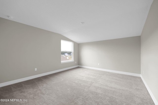 spare room featuring light colored carpet and lofted ceiling