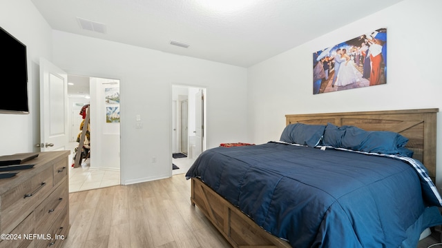 bedroom with light hardwood / wood-style floors and ensuite bath