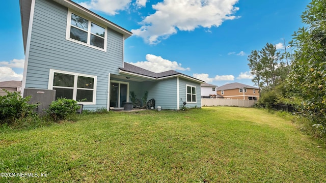 back of property featuring a lawn and cooling unit