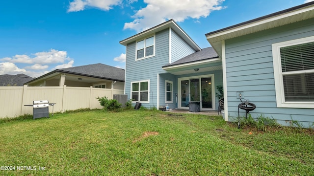 back of property with a lawn and central AC