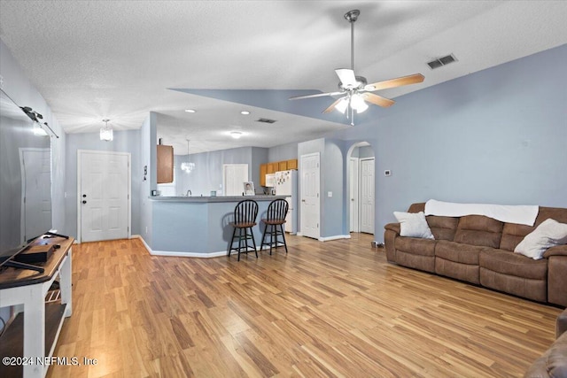 living room with a textured ceiling, light hardwood / wood-style flooring, and ceiling fan